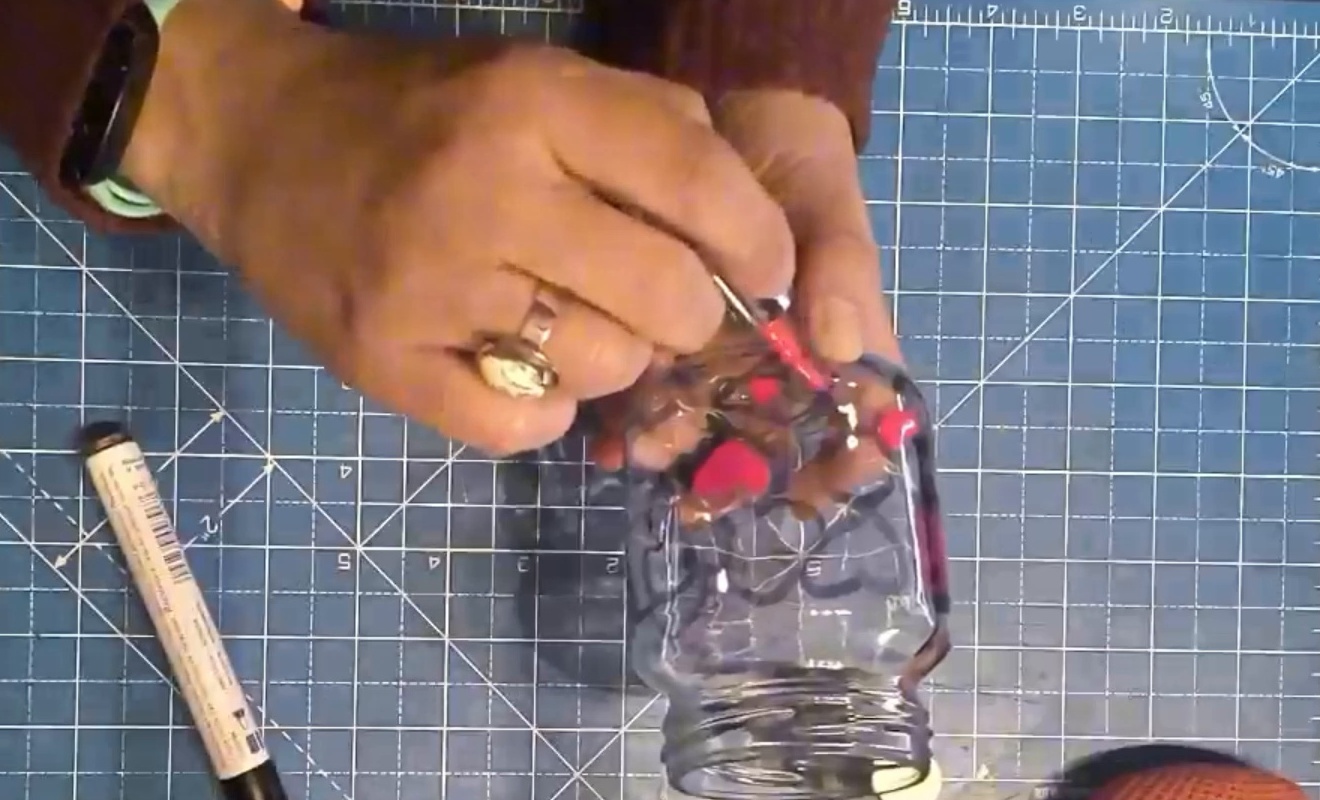 Manos de Nuria decorando a mano un bote de cristal durante un taller